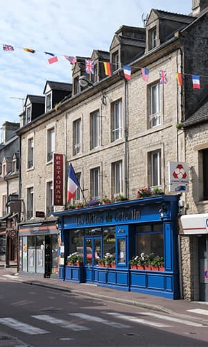 immeubles dans rue avec vitrine bleue du restaurant "Les Délices du Cotentin" à Sainte mère église.