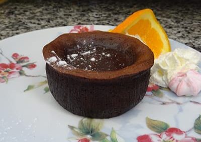 Gateau chocolat rond sur une assiette avec fleurs, du restaurant "Les Délices du Cotentin" à Sainte mère église.