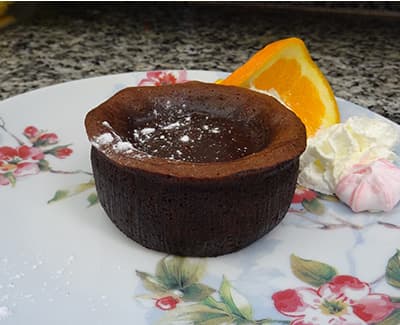 Gateau chocolat rond sur une assiette avec fleurs, du restaurant "Les Délices du Cotentin" à Sainte mère église.