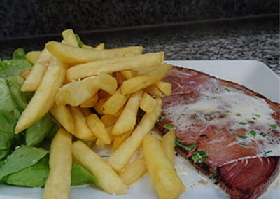 Tranche de Jambon épaisse avec sauce, frites et salade sur assiette blanche du restaurant "Les Délices du Cotentin" à Sainte mère église.