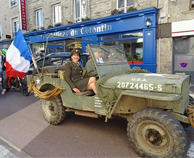 jeep avec un drapeau français et une femme devant le restaurant "Les Délices du Cotentin".