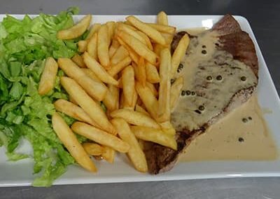 Steak avec sauce poivre vert et frites et salade verte.